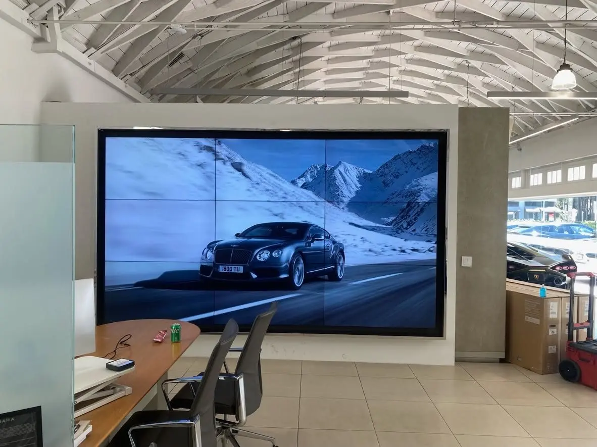 Three-by-three video wall playing automotive footage in a car showroom