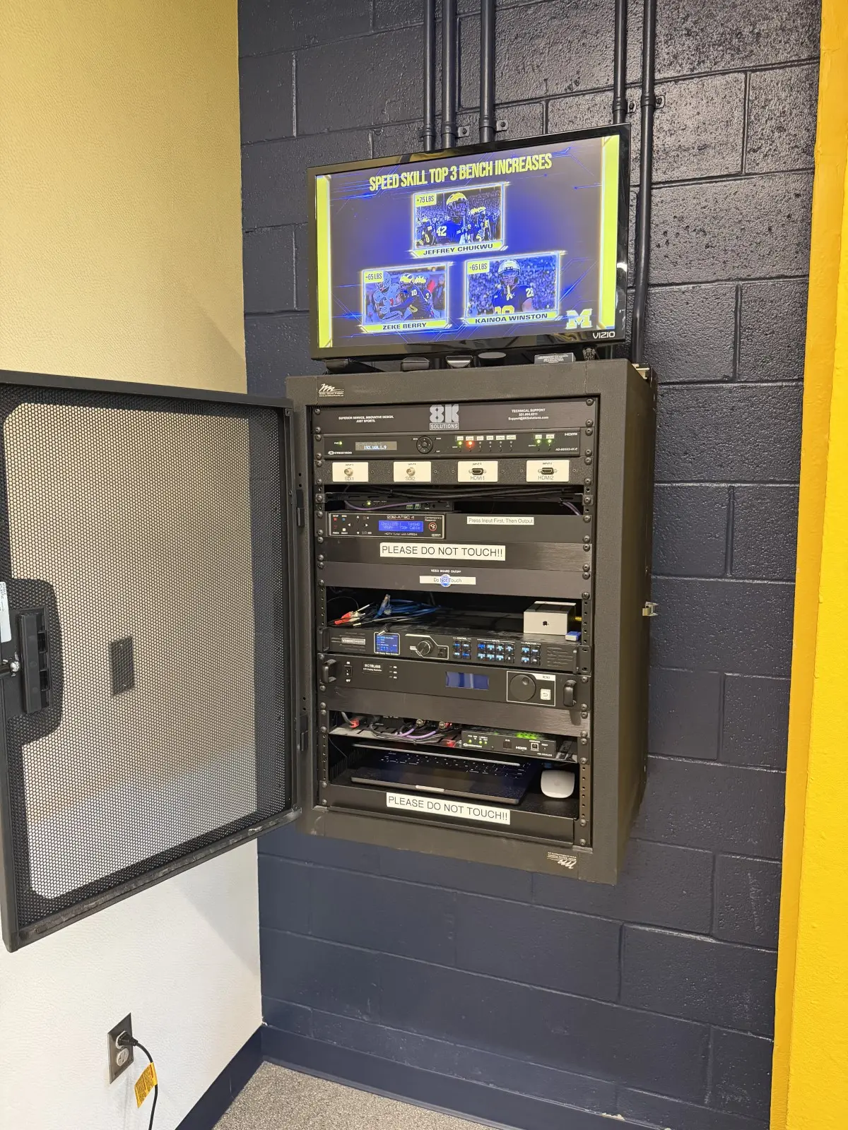Wall-mounted equipment rack with its door open, a display mounted above it