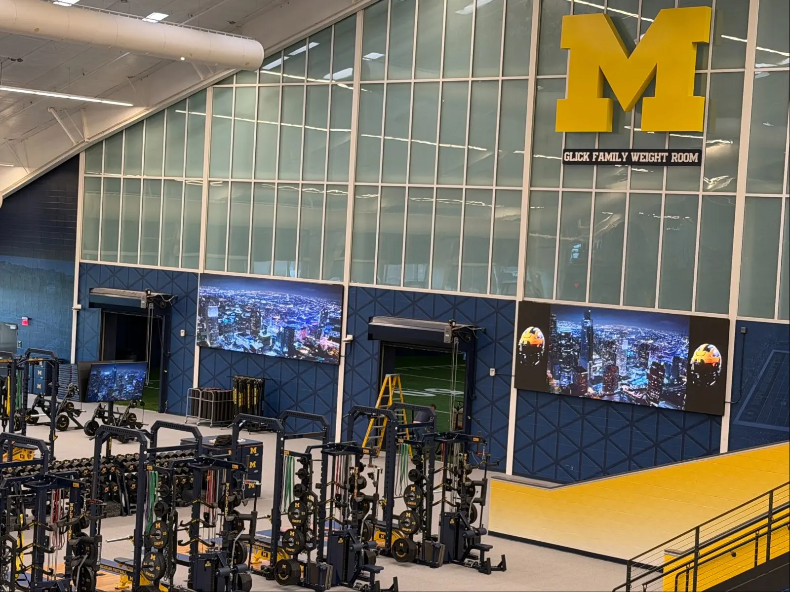Long LED video walls mounted along the wall of a football weight room
